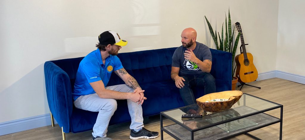 two men talking on a couch